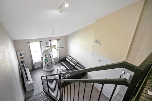 stairs featuring hardwood / wood-style flooring and track lighting