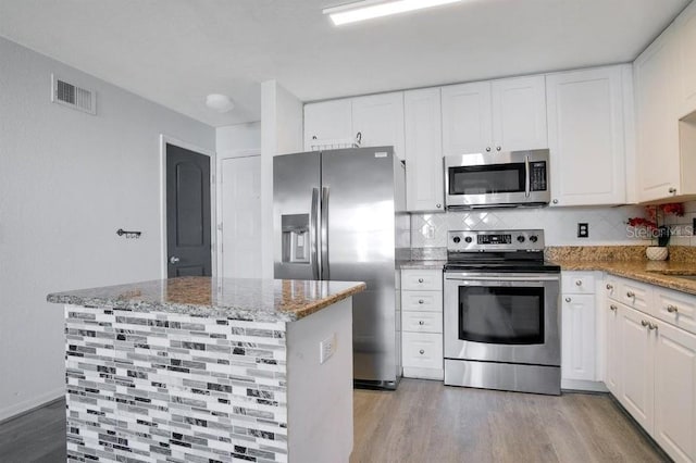 kitchen with stainless steel appliances, white cabinets, and light hardwood / wood-style floors