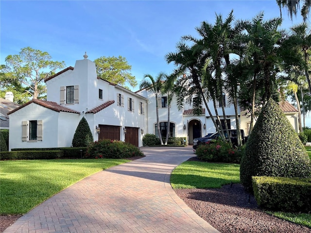 mediterranean / spanish home featuring a garage and a front yard