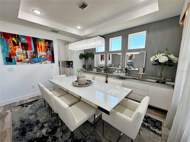 dining area featuring a raised ceiling and a textured ceiling