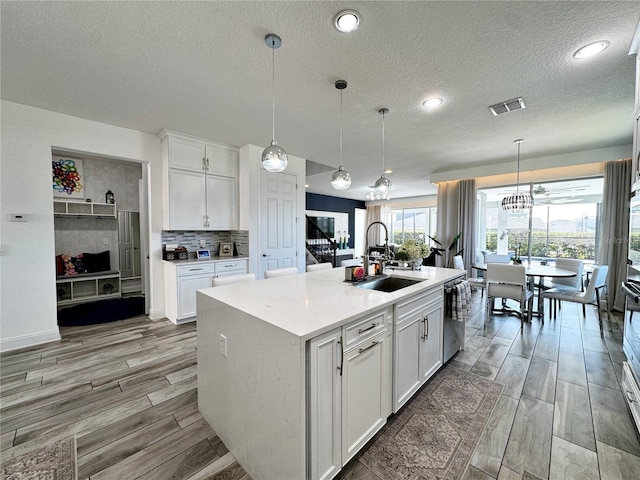 kitchen featuring white cabinetry, sink, and a kitchen island with sink