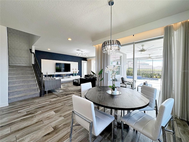 dining space featuring a healthy amount of sunlight, ceiling fan with notable chandelier, and a textured ceiling