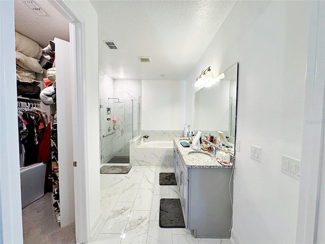 bathroom featuring vanity, independent shower and bath, and a textured ceiling