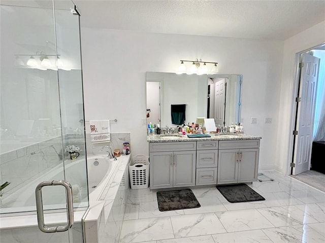 bathroom featuring vanity, a relaxing tiled tub, and a textured ceiling