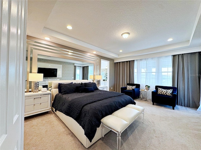 bedroom with a raised ceiling, light colored carpet, and a textured ceiling