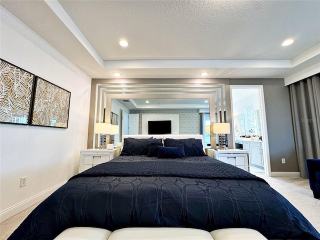 bedroom featuring light carpet, ensuite bath, a raised ceiling, and a textured ceiling