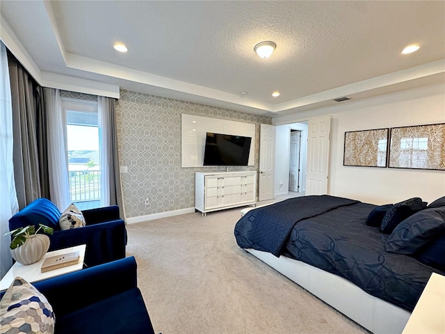 bedroom featuring a tray ceiling, carpet floors, and a textured ceiling