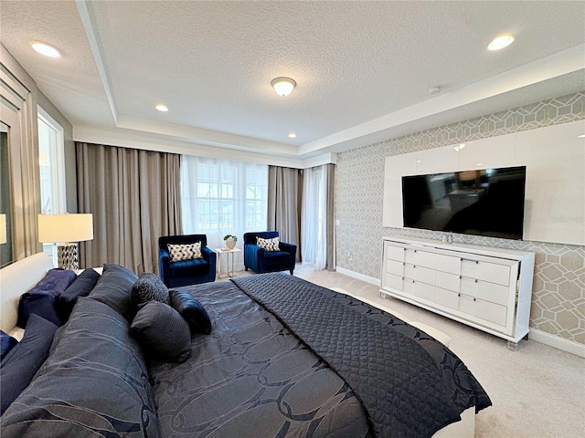 bedroom with a tray ceiling, carpet floors, multiple windows, and a textured ceiling