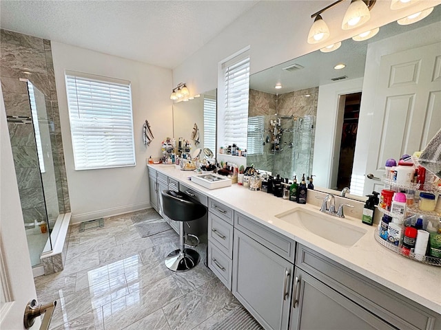 bathroom featuring plenty of natural light, a shower with door, vanity, and a textured ceiling