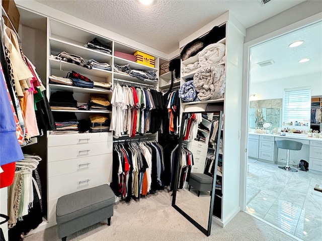 walk in closet featuring built in desk and light colored carpet