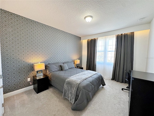 bedroom with light colored carpet and a textured ceiling