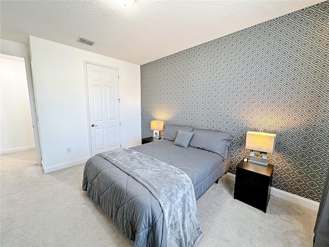 bedroom featuring light carpet and a textured ceiling