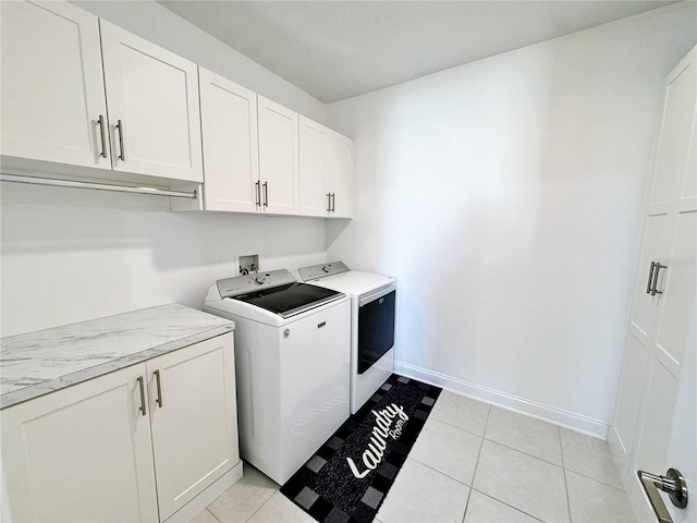 clothes washing area with cabinets, light tile patterned flooring, and washing machine and clothes dryer