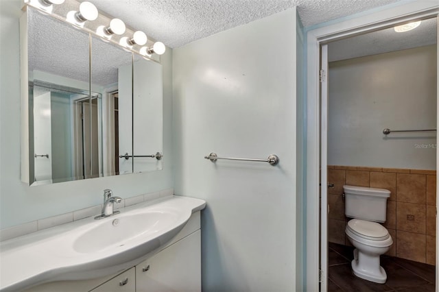 3002 Clubview Dr, Orlando, FL 32822 - full bathroom featuring a textured ceiling, vanity, toilet, tile walls, and tile patterned flooring