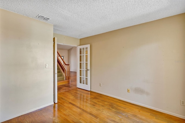 3002 Clubview Dr, Orlando, FL 32822 - empty room featuring stairs, wood finished floors, baseboards, a textured ceiling, and french doors