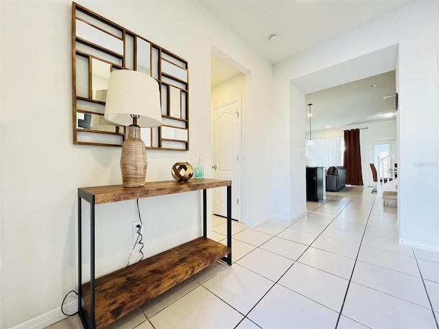 corridor with light tile patterned flooring and baseboards