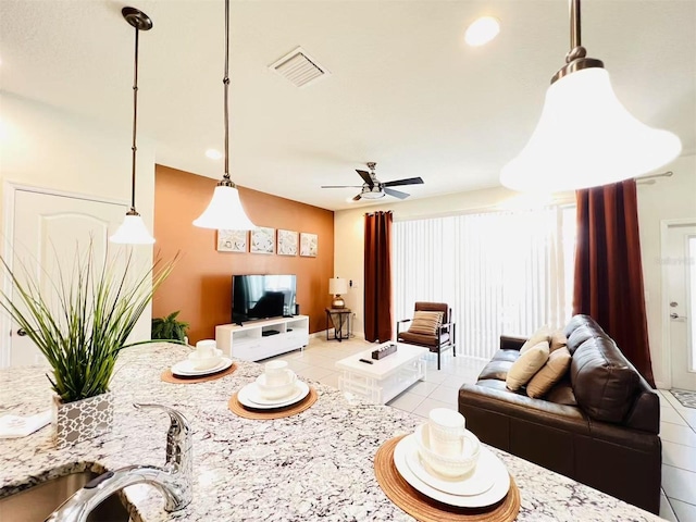 living area featuring light tile patterned floors, visible vents, and ceiling fan