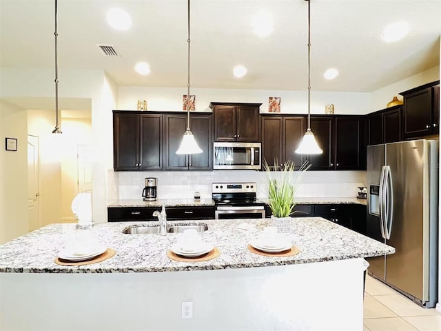 kitchen with visible vents, a sink, stainless steel appliances, decorative light fixtures, and tasteful backsplash