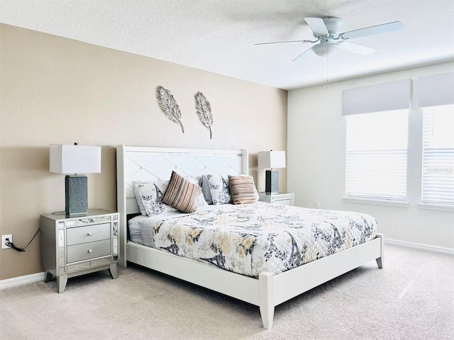 bedroom with light colored carpet, a textured ceiling, and baseboards