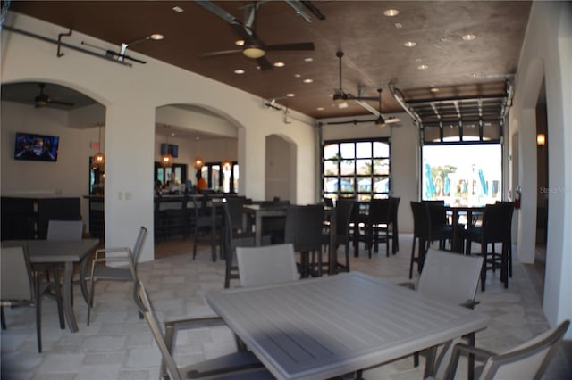 dining area with arched walkways and ceiling fan