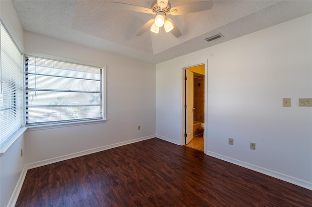 unfurnished room featuring dark wood-style flooring, visible vents, a textured ceiling, and baseboards