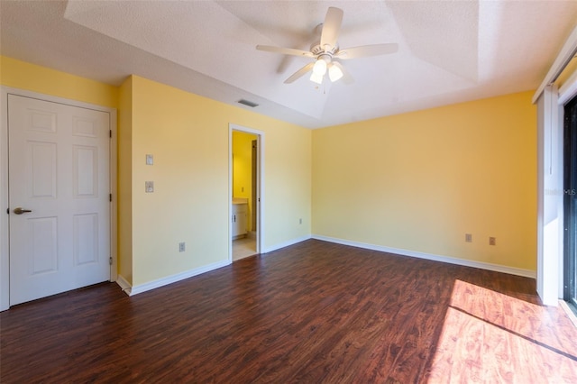 empty room featuring baseboards, visible vents, ceiling fan, dark wood-type flooring, and a tray ceiling