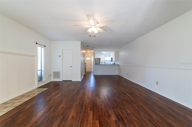 unfurnished living room with dark wood-style floors, visible vents, and a wealth of natural light