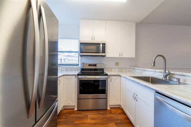 kitchen with light stone counters, dark wood finished floors, stainless steel appliances, white cabinets, and a sink