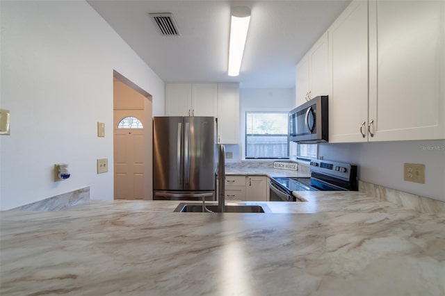 kitchen with light stone counters, visible vents, appliances with stainless steel finishes, white cabinetry, and a sink