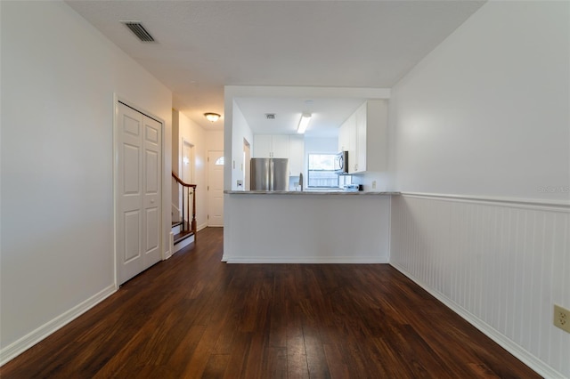 unfurnished living room with stairs, visible vents, and dark wood-type flooring