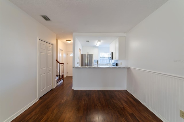 interior space featuring a wainscoted wall, visible vents, dark wood finished floors, and stairway