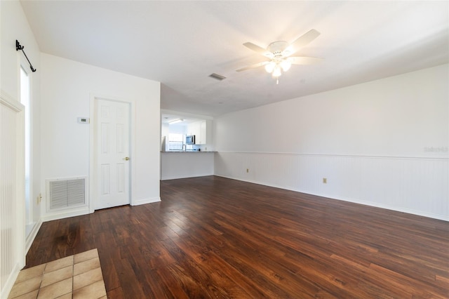 unfurnished room with dark wood-style floors, wainscoting, visible vents, and a ceiling fan