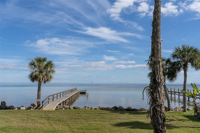 view of dock with a yard and a water view