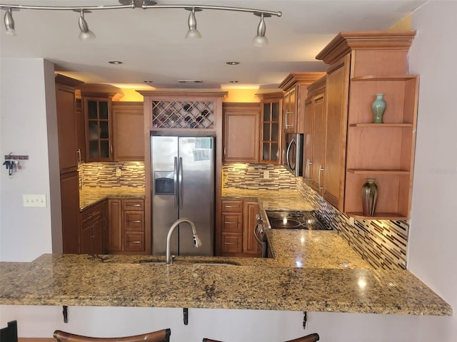 kitchen with sink, a kitchen breakfast bar, kitchen peninsula, stainless steel appliances, and light stone countertops