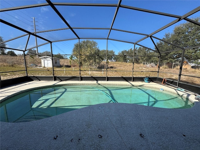 view of swimming pool featuring a lanai, a patio area, and a shed