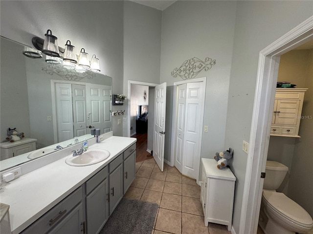 bathroom featuring vanity, toilet, tile patterned flooring, and a high ceiling