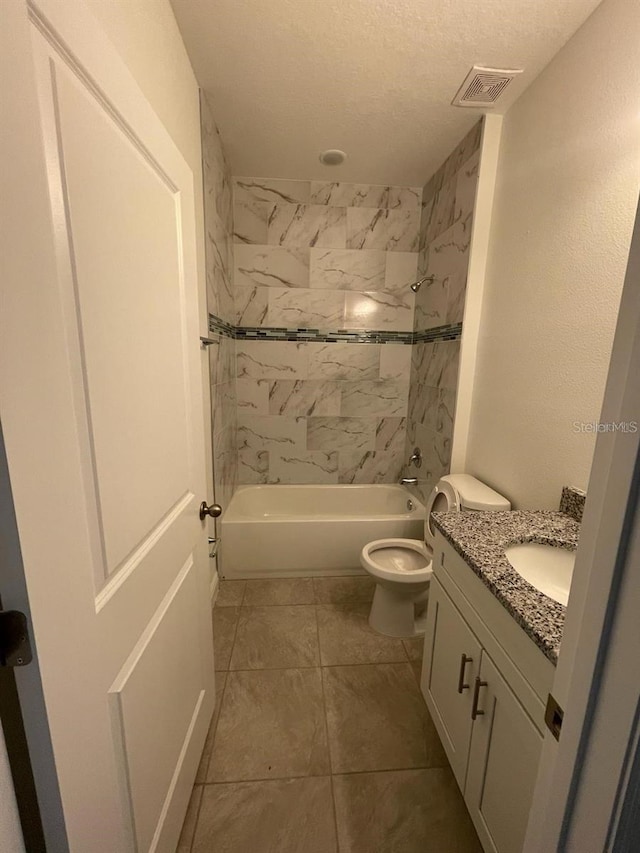 full bathroom with tiled shower / bath, vanity, toilet, and a textured ceiling