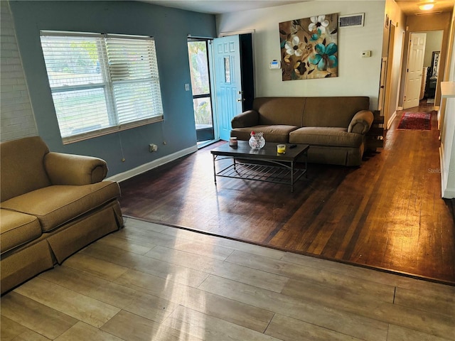 living area with visible vents, baseboards, and wood finished floors