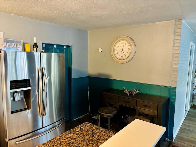 kitchen with a textured ceiling and stainless steel refrigerator with ice dispenser