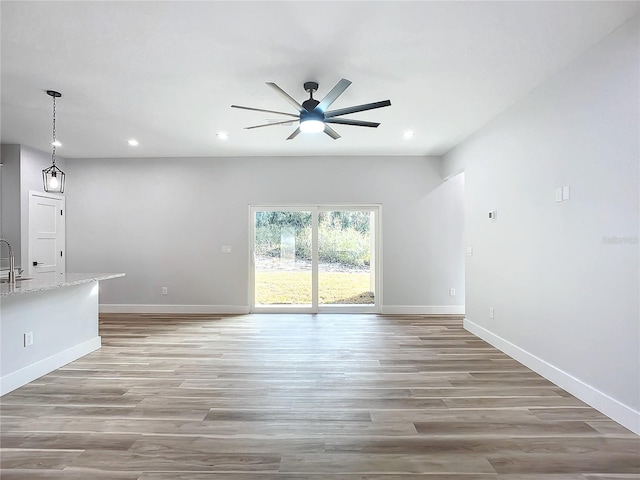 unfurnished living room featuring light wood-type flooring, sink, and ceiling fan