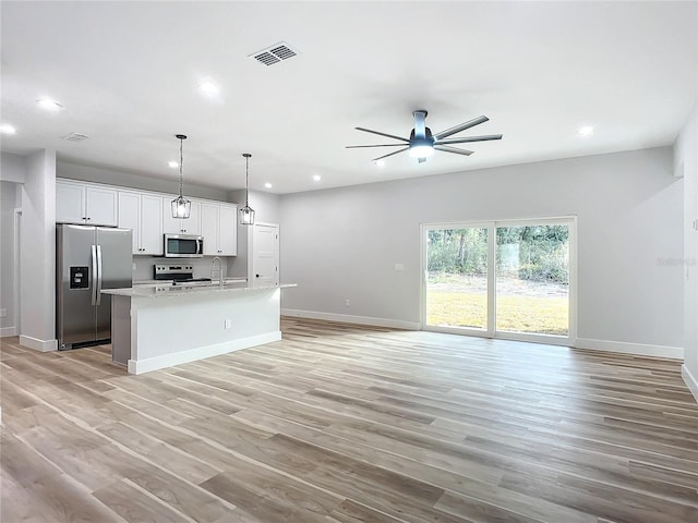 kitchen with appliances with stainless steel finishes, an island with sink, pendant lighting, ceiling fan, and white cabinets