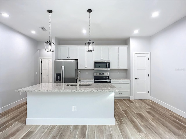 kitchen with sink, light stone counters, an island with sink, stainless steel appliances, and white cabinets