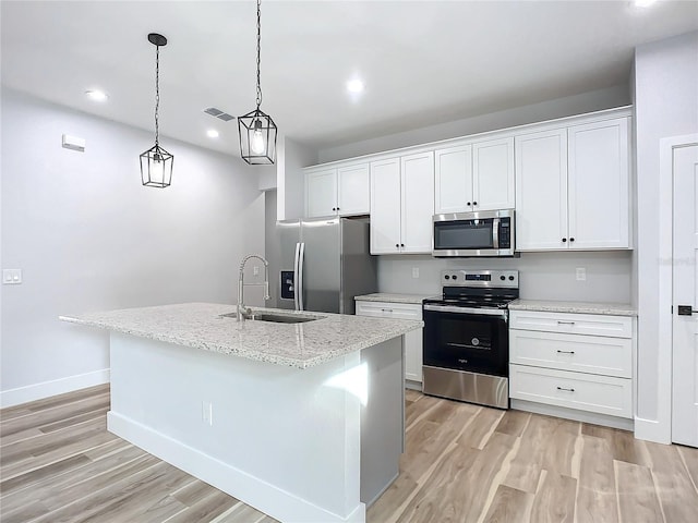 kitchen featuring stainless steel appliances, white cabinetry, sink, and a center island with sink