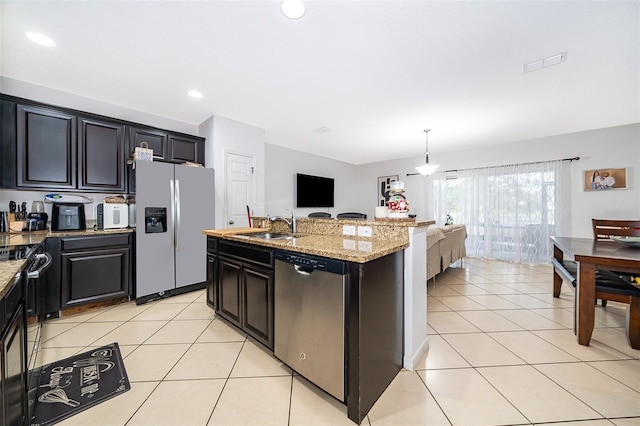 kitchen with pendant lighting, light tile patterned floors, a kitchen island with sink, stainless steel appliances, and light stone counters