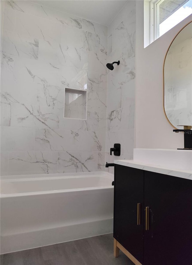 bathroom with vanity, hardwood / wood-style flooring, and tiled shower / bath