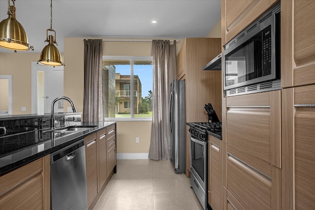 kitchen with appliances with stainless steel finishes, decorative light fixtures, sink, and dark stone countertops