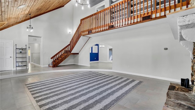 unfurnished living room featuring a towering ceiling, a chandelier, tile patterned flooring, and wooden ceiling