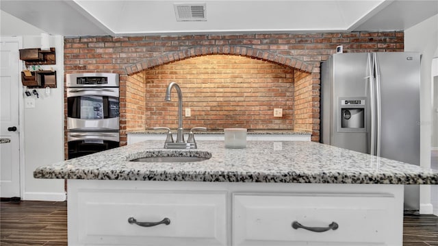 kitchen with brick wall, sink, and light stone counters