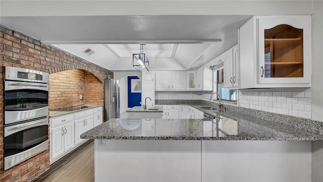 kitchen featuring vaulted ceiling, appliances with stainless steel finishes, sink, and kitchen peninsula