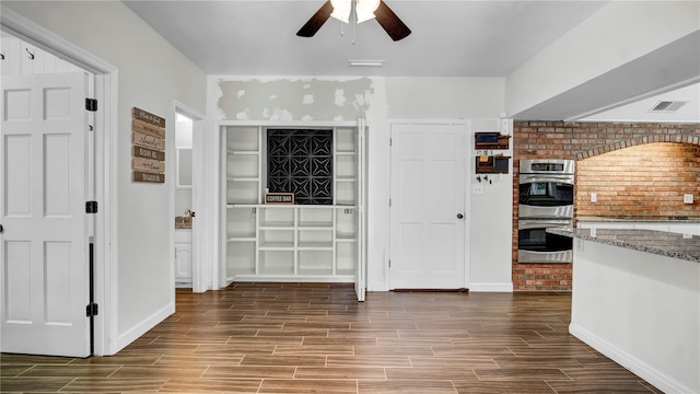 interior space with ceiling fan, light stone counters, and double oven